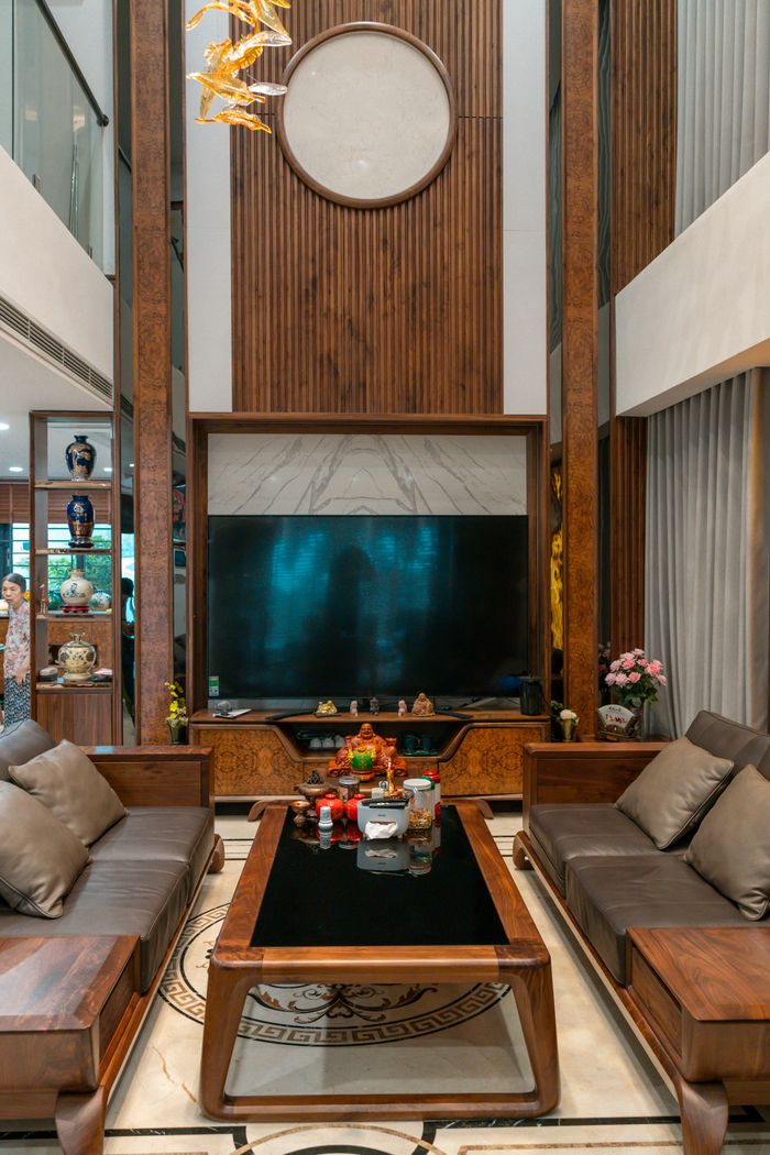Elegant living room with wooden accents, plush sofas, and a large TV creating a cozy ambiance.