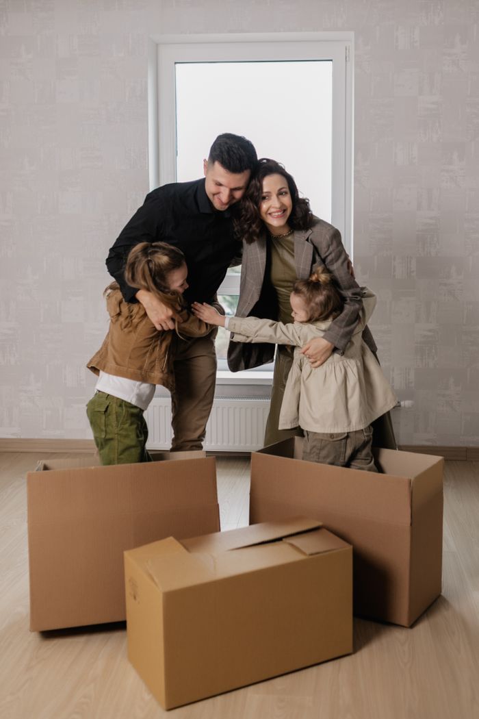 Happy family embracing in new home surrounded by boxes and smiles.